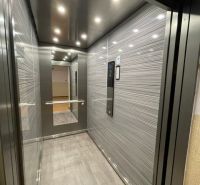 Elevator in a building with a wooden decor floor and a large mirror.