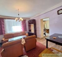 Living room of a family house with an orange sofa set and a cabinet ensemble.