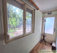 A narrow hallway in a family house with a window, a coat rack, and a wooden decor floor.