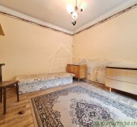 A room with a bed, a chair, and carpets, a floor with a wooden decor, corner furniture.