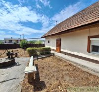 A family house in Kamenica nad Hronom with a yard, a well, and a bench on a sunny plot.