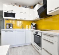 A kitchen in a 3-room apartment with white cabinets and yellow tiles.