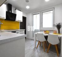 A kitchen in a 3-room apartment with white furniture and yellow tiles by the stove.