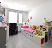 Children's room in a three-room apartment with toys and a writing desk, floor with wooden decor.