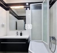 A bathroom in a 3-room apartment with a bathtub, a sink, and a floor with a wooden decor.