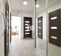 A hallway in a 3-room apartment with a mirrored wardrobe and a wooden decor floor.