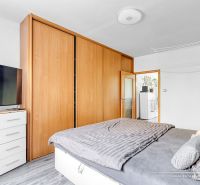 A bedroom in a two-room apartment with a wooden decor floor and a built-in wardrobe.