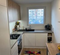 A kitchen in a 3-room apartment with a wood-patterned floor and a large window.