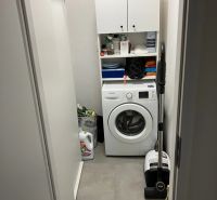 Laundry room with a washing machine and storage cabinets in a 3-room apartment.
