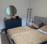 A bedroom with a bed, a dresser, and a round mirror in a 3-room apartment.