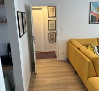 Light wood-effect flooring and a yellow sofa in a 3-room apartment.