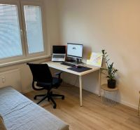 A workspace in a 3-room apartment with a wooden decor floor and a sofa bed.