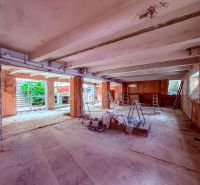 Under-construction commercial spaces with concrete flooring, ladders, and building materials.