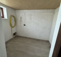 Laundry room with tiled floor and ceiling with wooden decor in a family house.