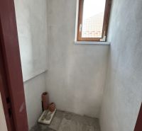 A small room with a window in a family house, unpainted walls, tiled floor.
