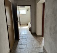 A hallway in a family house with tiles and a window, without visible furniture.