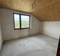 A view into an empty room of a family house with a skylight and a concrete floor.