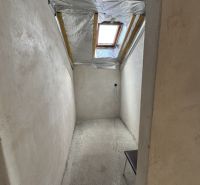 A narrow room with a concrete floor and a skylight in a family house.