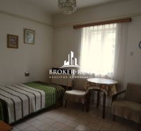 A room in a family house with a bed, chairs, and a table, decorative paintings on the wall.