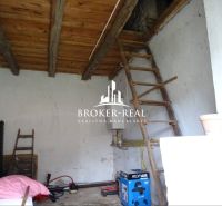 Interior of a family house with a wooden ceiling and a ladder, furnished with tools and crates.
