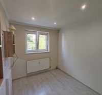 A room in a 3-room apartment with a wooden decor floor, a wall lamp, and a radiator.