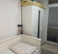 A room with a bed, wardrobe, and rolled-up mattresses in a 2-room apartment.