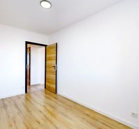 A room in a 3-room apartment with a wooden decor floor and white walls.