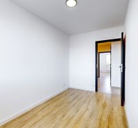 A spacious room in a 3-room apartment with a wooden decor floor and white walls.