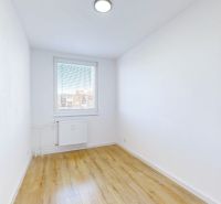 A room in a three-room apartment with a wooden decor floor and white walls.