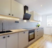 The kitchen in the 3-room apartment has a wooden decor floor and modern equipment.