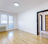 A room in light tones with a wooden decor floor in a 3-room apartment.