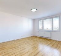 A spacious room with large windows and a wooden decor floor in a 3-room apartment.