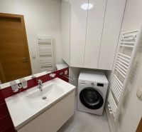 A bathroom in a 3-room apartment with a washing machine, sink, and storage space.