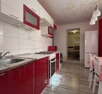 A kitchen in a family house with red cabinets and a dining table with a checkered tablecloth.