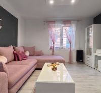 Living room in a family house with a pink sofa and white furniture.