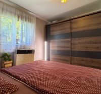 Bedroom in a family house with a large wardrobe and a bed with a polka dot blanket.