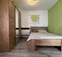 A bedroom in a family house with a bed, a wardrobe, and a floor with a wooden decor.