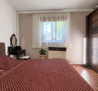A bedroom in a family house with decorative curtains and a wooden decor floor.