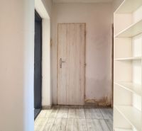 A hallway in a family house with tiles and a white bookshelf.