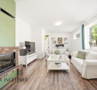 Living room with a fireplace, TV stand, and wooden decor flooring in a three-room apartment.