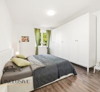 A bright bedroom with a large bed, wardrobe, and wooden decor flooring in a 3-room apartment.