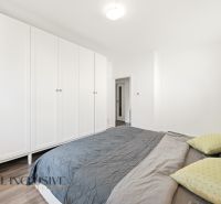 A bedroom in a three-room apartment with a white wardrobe and a wooden decor floor.