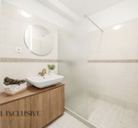 Bathroom in a 3-room apartment with a sink, mirror, and shower corner, white tiles.