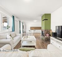 Living room in a three-room apartment with a wooden decor floor and a fireplace.