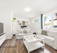 A bright living room with white furniture and a wooden decor floor in a 3-room apartment.