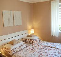 A bedroom with two beds and decorative paintings in a three-room apartment.