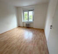 A room in a two-room apartment with a wooden decor floor and a large window.