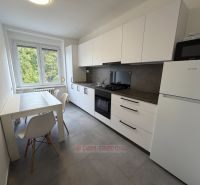 The kitchen in a 2-room apartment with a light dining table and white cabinets.