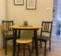 Dining nook in a 2-room apartment with black chairs and a table on a floor with a wooden decor.