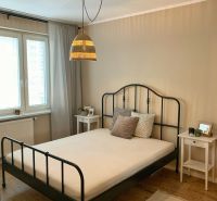 Bedroom in a 2-room apartment with a metal bed and wood-patterned flooring.